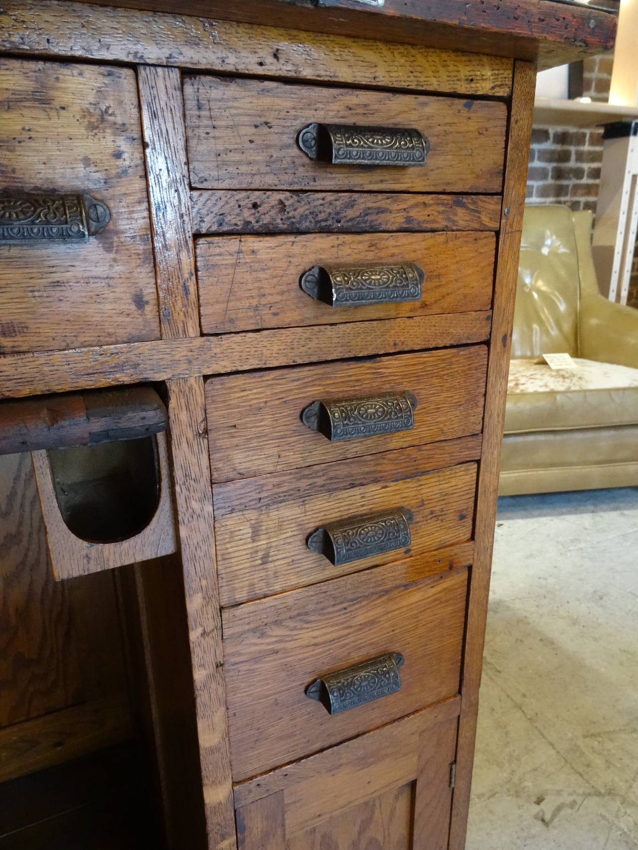 Oak jewelers desk from the early 1900's.  Original, rich, golden patina with raised panels, finished with a steel top and industrial accents.  Boasting 10 drawers, 2 doors, and a center, pullout catch-all.  Has a secret locking mechanism, located in