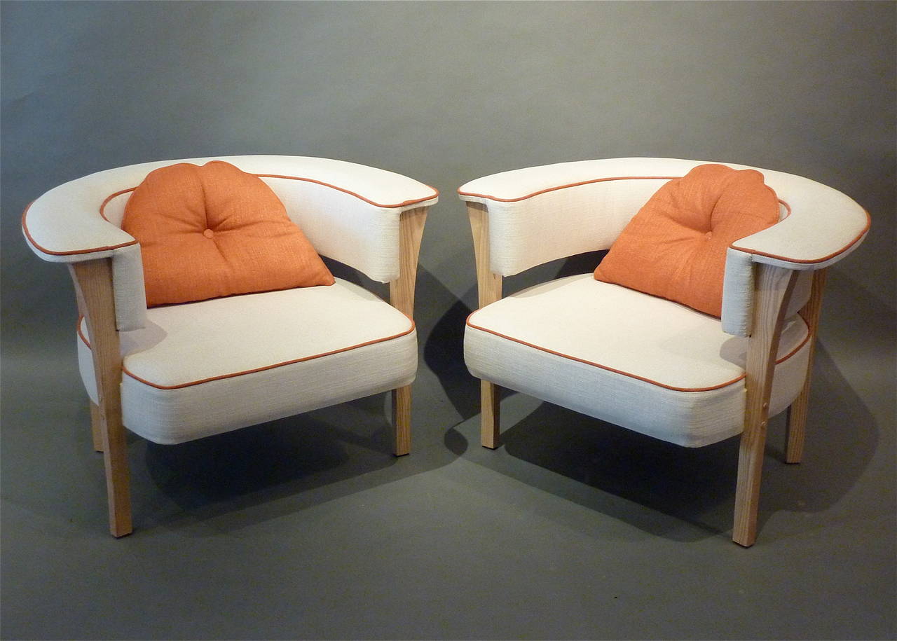 Unusual pair of Mid-Century Modern armchairs. Upholstered in natural linen with orange piping and with orange accent pillows. Extremely comfortable with horseshoe shaped arms over tapering legs made of ash, Denmark, circa 1960.