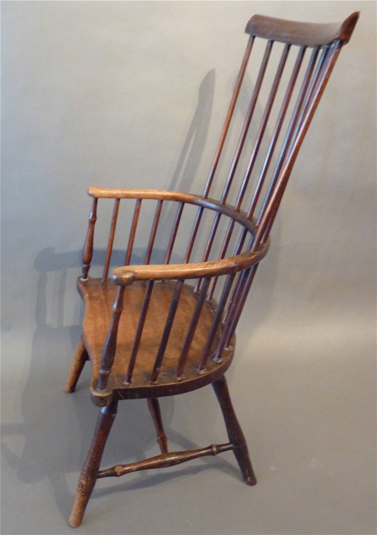 18th Century English “Comb-Back” Windsor Armchair. Made of Ash, Elm, and Walnut with a deep, lustrous color and warm patination. Delicate spindles and elegant curved arms over a “saddle” seat with simply turned legs and stretchers. Extremely
