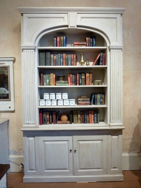 Pair of Georgian Style Architectural Bookcases. The cornice with shaped panels centering on a tapering keystone over an arched opening inset with shelves flanked by fluted pilasters above a pair of paneled doors. Constructed from facades originally