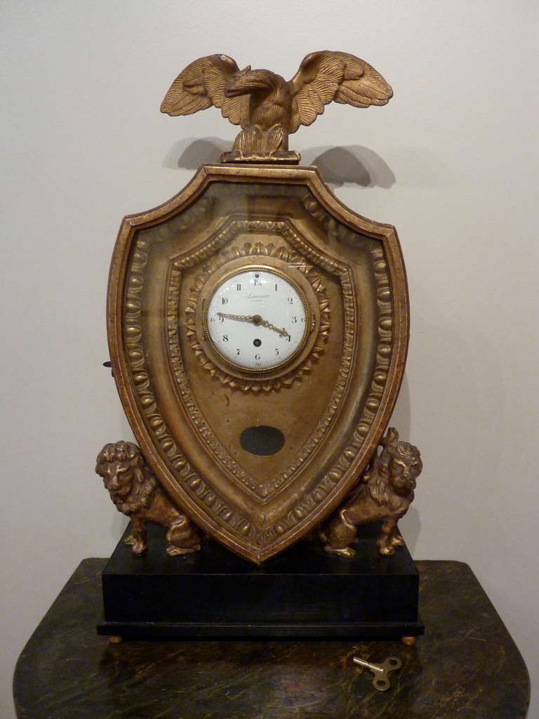 Fine and Rare Charles X 18th Century French Mantel Clock.  Mounted on and ebonized base gilded ball feet.  Two intricately carved and gilded lions support a shield shaped case with carved egg and dart decoration surmounted with a carved and gilded