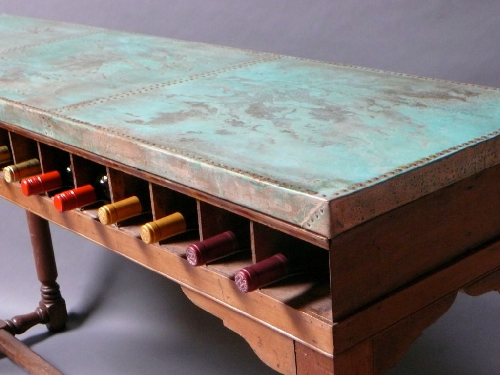 An Unusual 19th Century Clerks Desk With Copper Top And Wine Rack. Contemporary “ Verdigris “ Copper top over 16 cubby holes than can be used to store wine above shaped brackets and boldly turned pine legs with center stretchers. Made in England