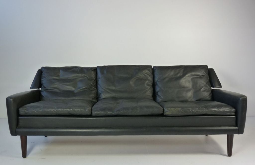 Danish sofa with original black leather.  Rosewood legs.  Matching chairs available.