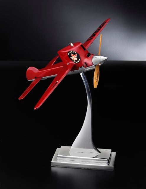 A classic American motorized control line model airplane mounted on a custom, polished aluminum stand.