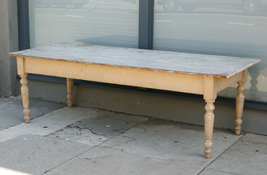 8 ft. long harvest farm table with original paint surface. Nearly 3.5 ft. wide  with a white plank top with cream skirting and legs. A solid and sturdy table with beautifully turned legs.  Found in the midwest.