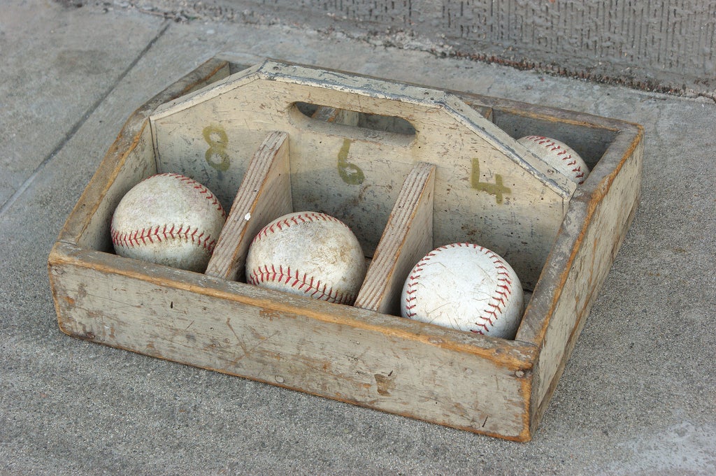A collection of six vintage softballs sits inside this compartmentalized and numbered sorting tray with it's original paint surface.