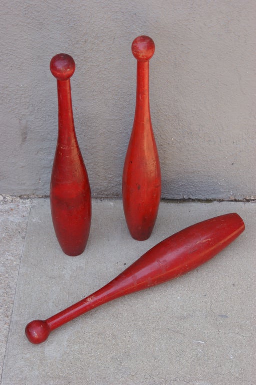 Great trio of Indian clubs in their original red paint surface. 

Indian clubs rose to popularity in the US during the health craze of the late Victorian era. Three Indian clubs were first repurposed for juggling by an American, DeWitt Cook, in