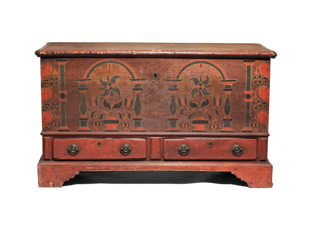 A rare and bright blanket chest in brilliant reds contrasted with blacks. The decoration is nicely painted with urns and flowers flanked by pillars and hearts on the corners. There is decoration on the sides and traces of decoration on the top. It