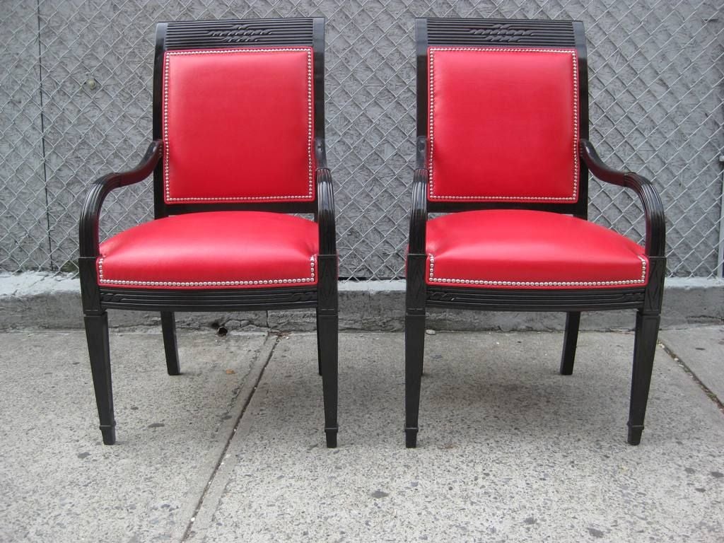 A gorgeous pair of large Moderne Mid Century hand-carved king chairs, in Hollywood Regency black lacquer with scarlet red leather and nail heads all around.

