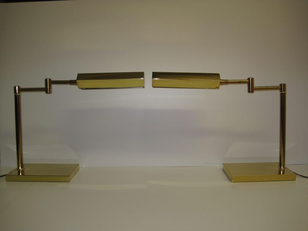 Pair of swivel head swing arm high polish brass desk lamps after Nessen, with age appropriate patina.
