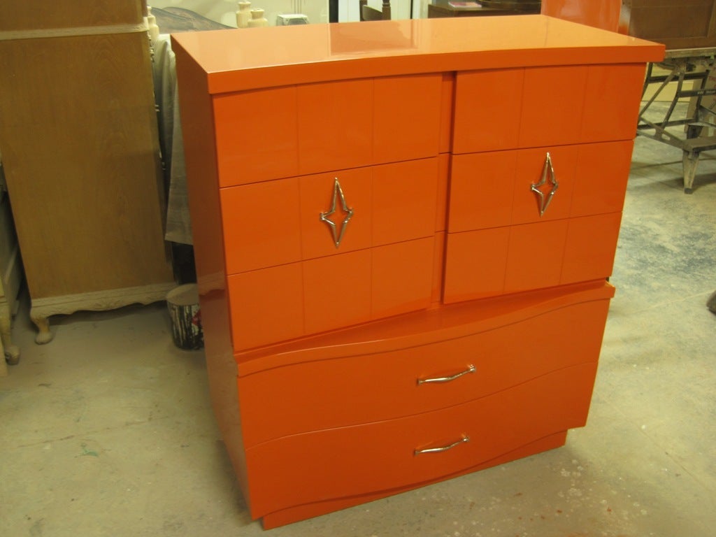 Combination of art deco serpentine and cubist Mid-Century modern elements puts this highboy tall dresser in spectacular orange lacquer this item is just a notch above all else.  This item is on sale for a clearance price.