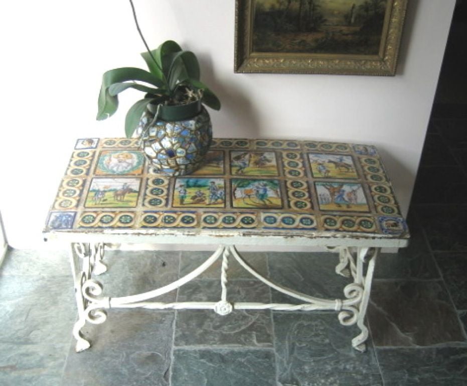 Antique French/Italian iron console table, early 20th century.  Scrolled, hand hammered iron, French base with an application of hand painted tiles.  The tiles are SPANISH in origin, featuring unique scenes related to DON QUIJOTE, each tile being
