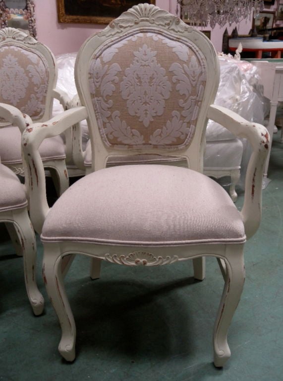 Vintage set of eight matching, French Country Dining Chairs.  Fabulous carved frames, generous seats, cottage white paint.  Upholstered with a nubby linen textile on the seats and backs; a sculpted fleur dy lis pattern flock linen on the inside