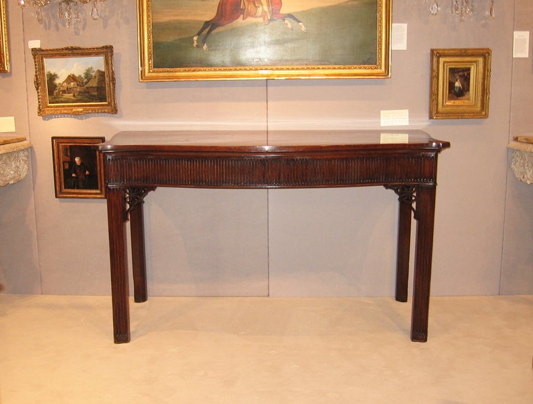 An English late 18th century George III period mahogany server; the serpentine shaped top to a conforming fluted apron above pierced fretwork carved brackets, all raised on square fluted legs.