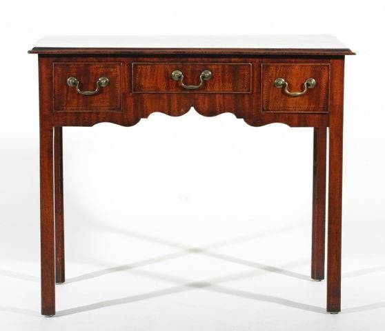 An English late 18th century George III period mahogany lowboy; the rectangular top with a moulded edge above a shaped three drawer apron, each drawer decorated with chequer line inlay; all raised on square chamfered legs.