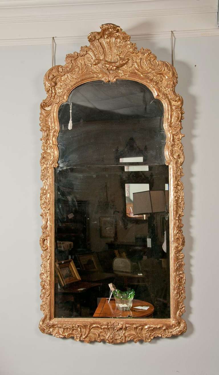 An early 18th century continental giltwood pier mirror.
Wonderful water gilt surface with superb carving a scale. 
This mirror would work well to enhance any room giving it scale and height. A must see. This type of giltwork was meticulously