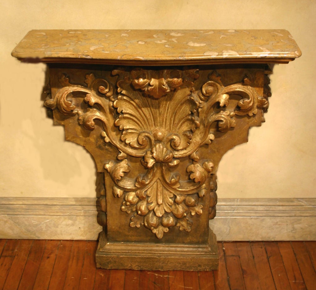 A continental shell carved parcel-gilt marble-top console table.