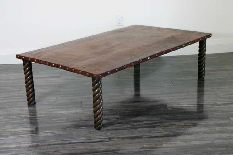 A Modern distressed, tooled leather top coffee table with decorative brass nailed edges, raised on spiral turned gesso faux bronze finished legs.