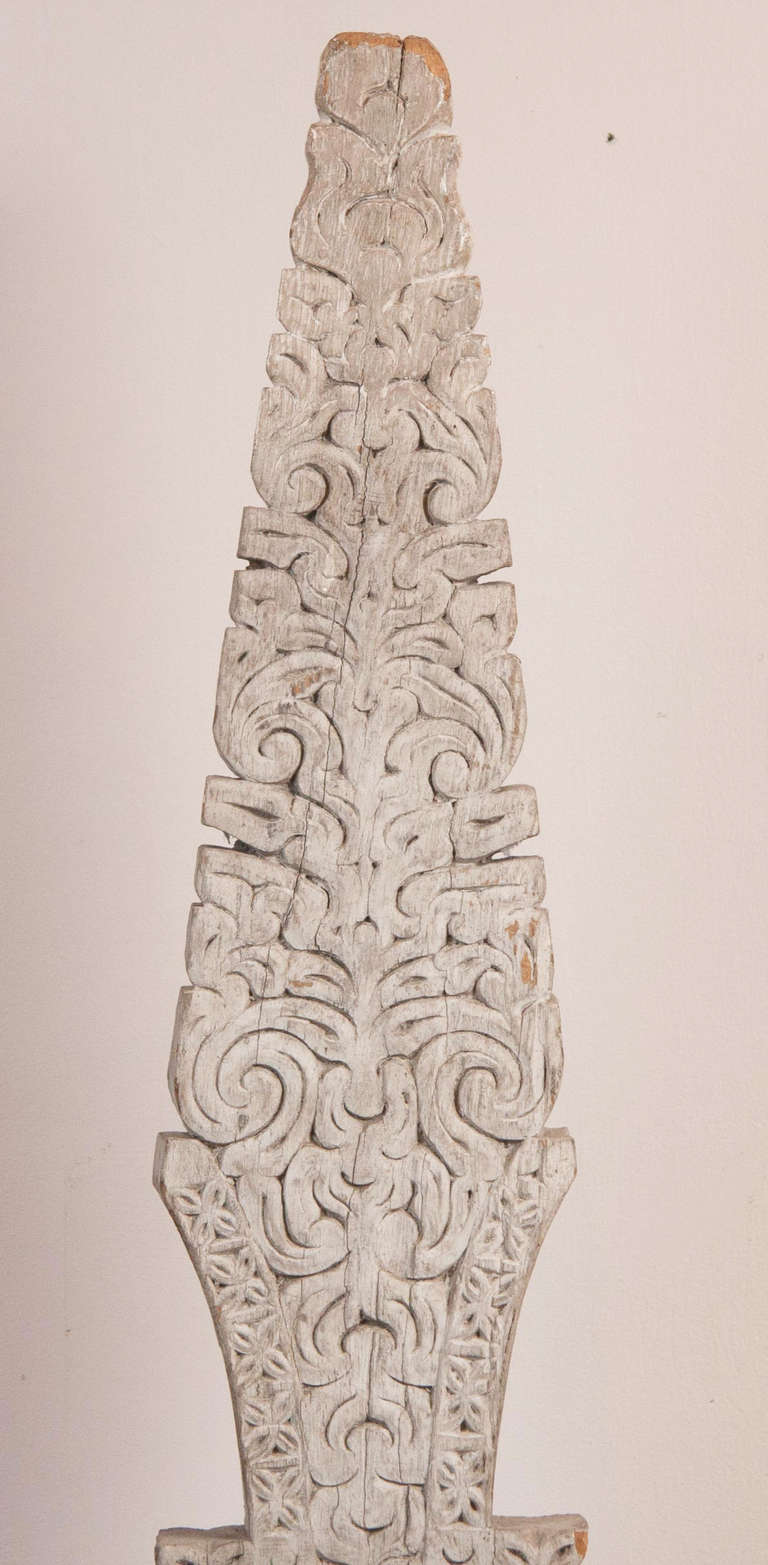 A Philippine 19th century carved and painted land marker with relief carving of foliage on both sides; raised on a metal stand.