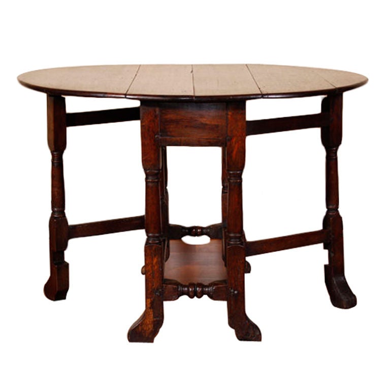 Early 18th C Oak gateleg table with typical country construction and plank top. Good color , worn and distressed wax finish, typical of the period. One foot re tipped.