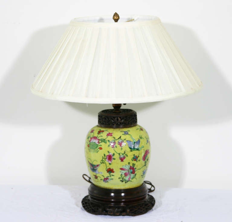 A Chinese mid-19th century vase with a yellow ground and foliate decoration on a carved, pierced wooden base, now as a lamp.