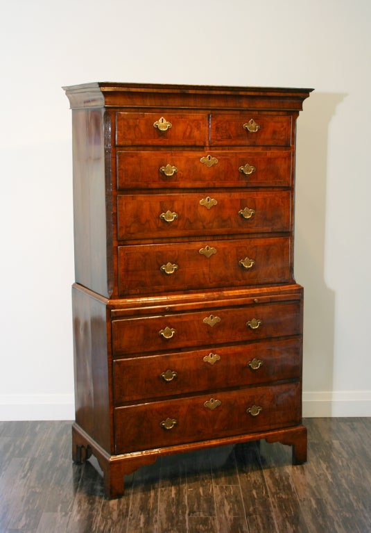 An early 18th century English walnut chest on chest, the cavetto moulded cornice above an upper section with two short and three long crossbanded and half feather herringbone inlaid ovolo moulded drawers flanked by fluted canted corners above a