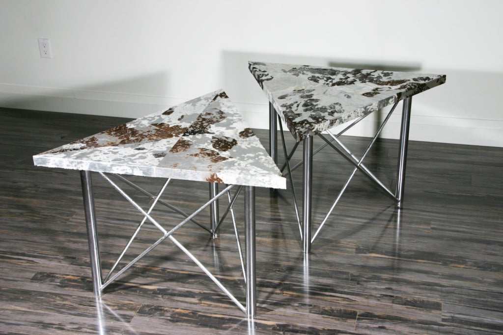 A pair of end tables with segmented acid etched goat skin tops raised on distressed chrome tubular 
