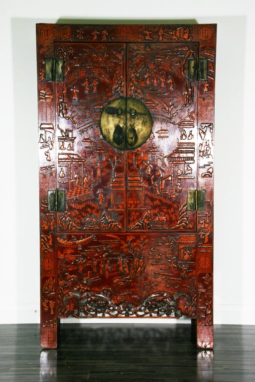 A late 18th-early 19th century Chinese red lacquer chinoiserie decorated two-door cabinet with a carved pierced apron.