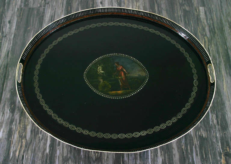 A late 18th century neo-classical tray table the oval top with a pierced fretwork gallery, decorated with a central oval painting of a classical scene of a woman in a garden with a statue.  Later stand.
