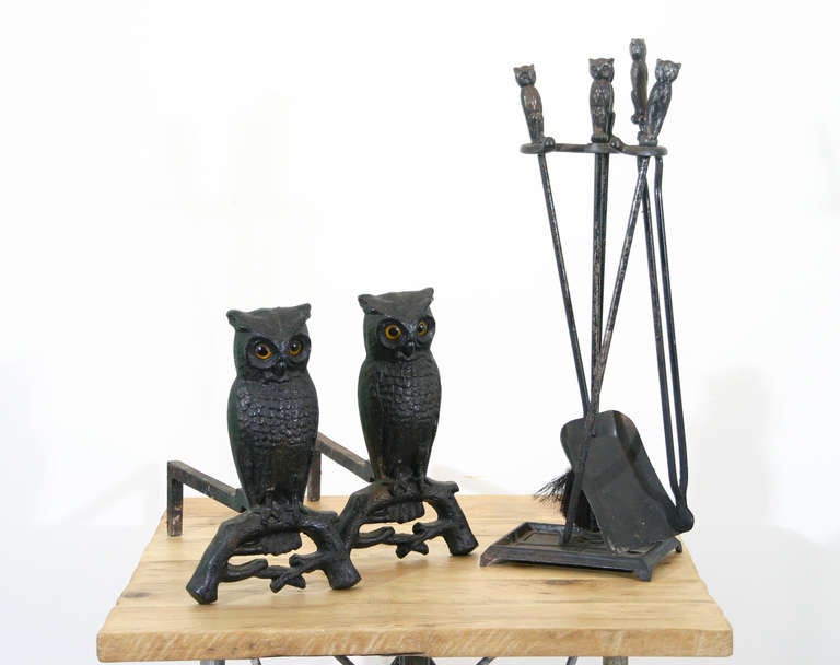 A late 19th century pair of iron Owl Form Andirons with glass eyes and a complete set of matching iron Fireplace Tools with owl finials.  Dimensions of Fire Tools: 27