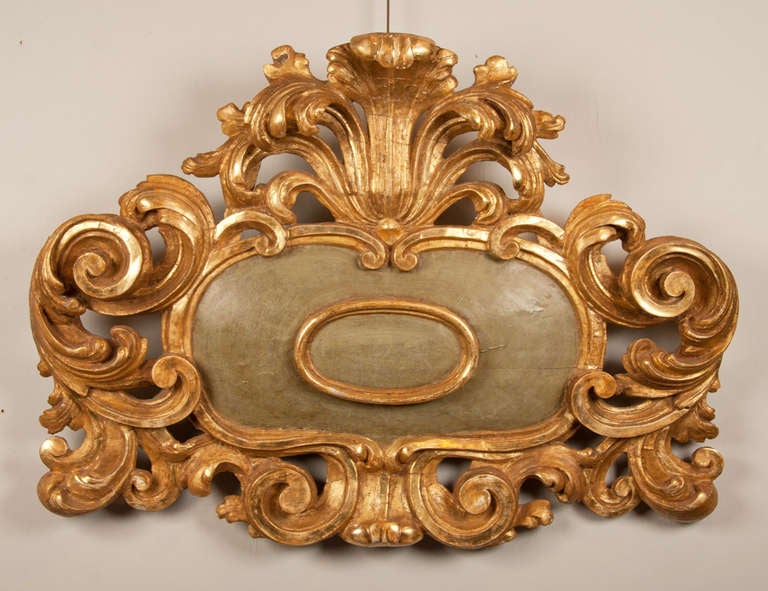 An Italian early 18th century Rococo cartouche form carved gilt and paint wall carving.