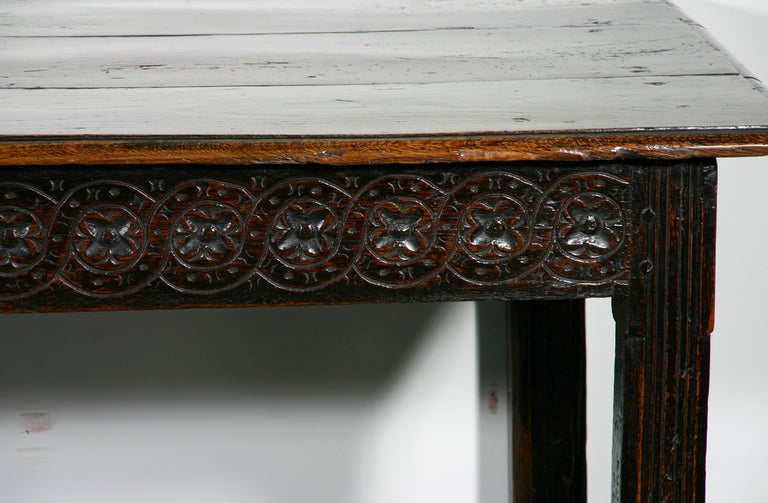 An Early 18th Century Oak Refectory Table; having fabulous color, relief carved apron and three board plank top.