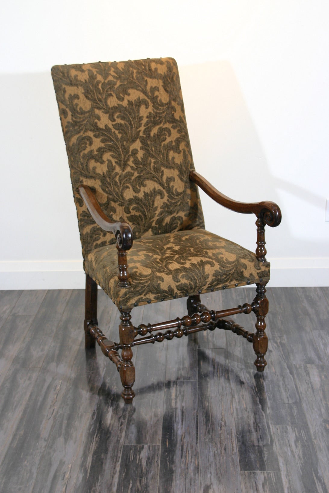 A French late 17th century Baroque walnut armchair with scrolled arms and turned legs and connecting stretchers.