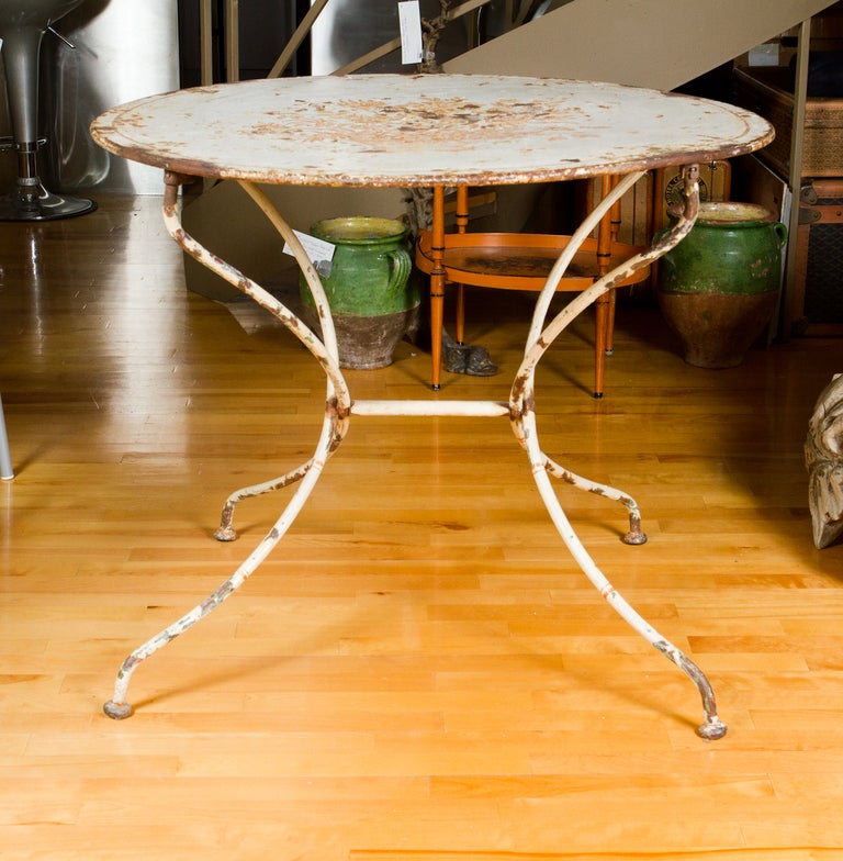 Beautiful painted south of France tole round garden table on four swept legs , the top  decorated with painted floral motif. The table folds to become flat.