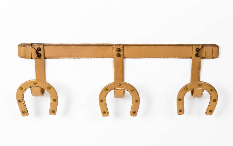 Unusual stitched beige leather coat hanger by Jacques Adnet in the form of three horse shoe hooks.