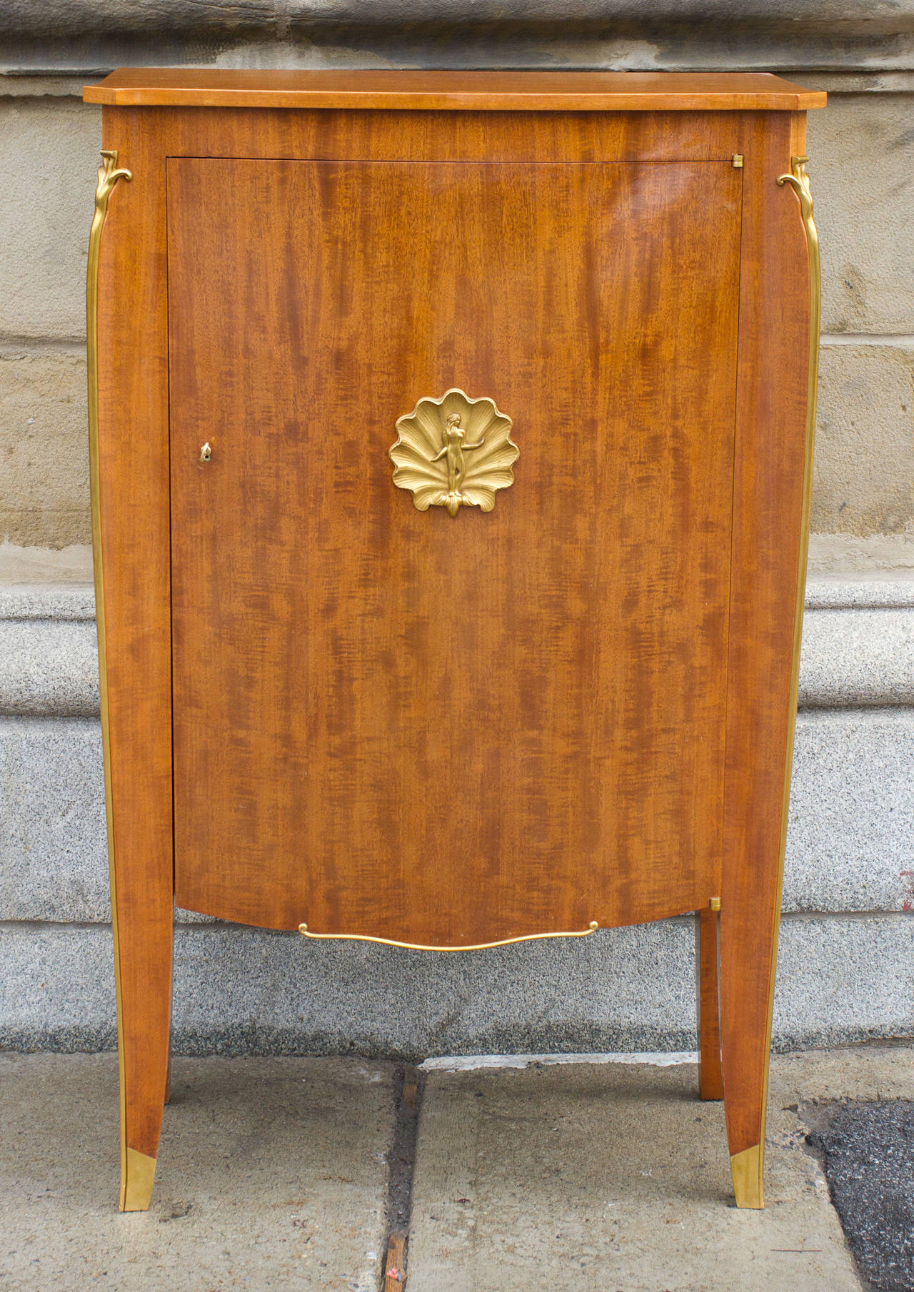 Elegante  mueble de caoba de Jules Leleu, bellamente provisto de monturas de bronce dorado diseñadas por Debarre y  Perret, el camafeo central con una representación de 