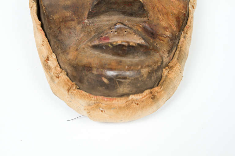 Afrikanische Dan-Maske von der Elfenbeinküste mit genähtem und genageltem Stoff.