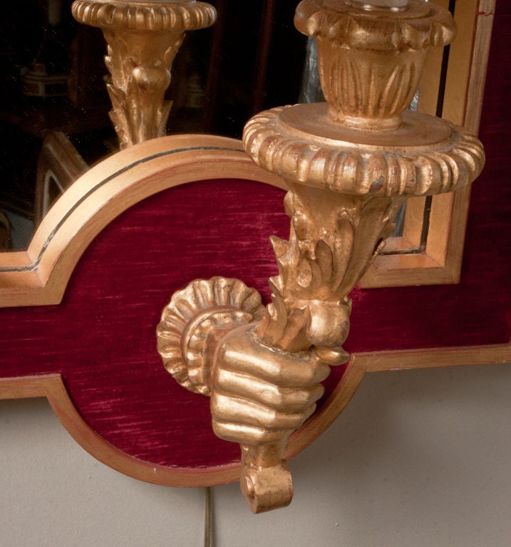 Interesting pair of carved giltwood sconce-mirrors, the mirror frames inset with red velvet.