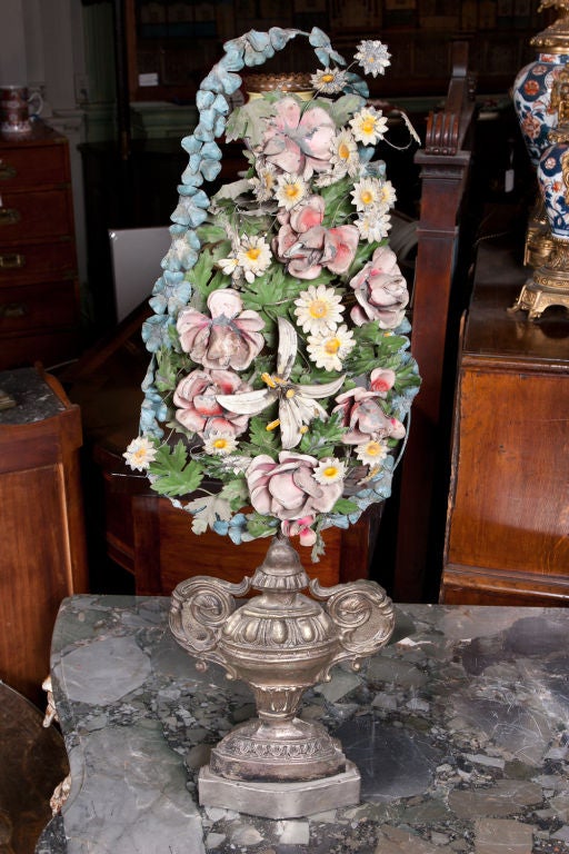 Pair of silver plated repoussé brass decorative urns fitted with polychrome painted tôle flower bouquets.