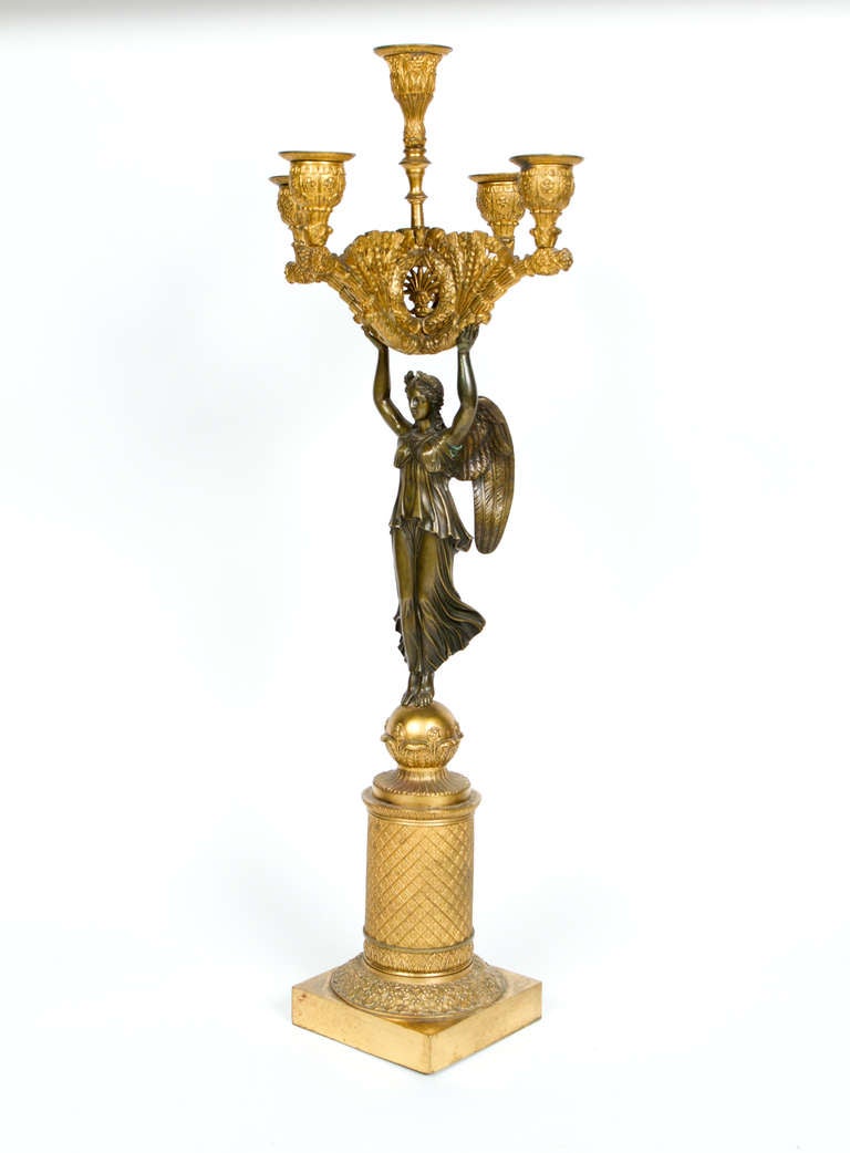 Pair of Charles X period gilt and patinated bronze candelabras featuring winged victories holding five light candle holders.