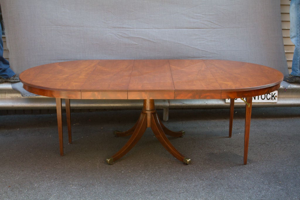 Regency style mahogany single pedestal circular extending dining table, the round top opens to extend with three leaves supported by four folding legs. 92 inches when fully extended.