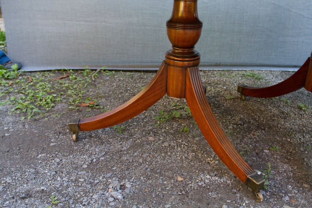 Fine quality mahogany Regency style double pedestal extending dining table, the top inlaid with mahogany cross-banding and ebony stringing, the two pedestals supported by reeded saber legs ending in bronze casters. Signed 