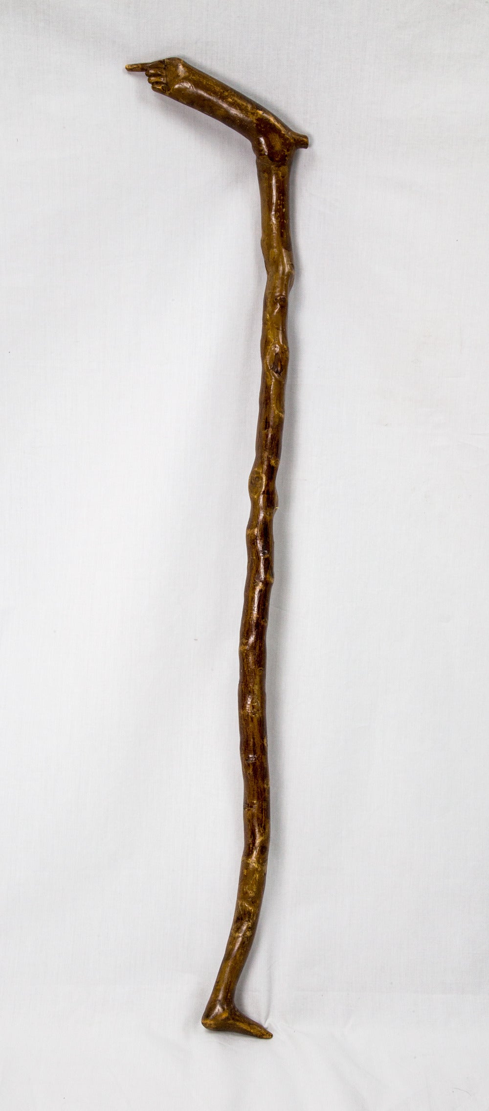 Unique Folk Art wood walking stick cane featuring a hand grip and a foot at the bottom; beautifully hand-carved with a wonderful feel. Great color and patina; measuring approximate 31” long x 0.866” diameter; circa early 20th century.