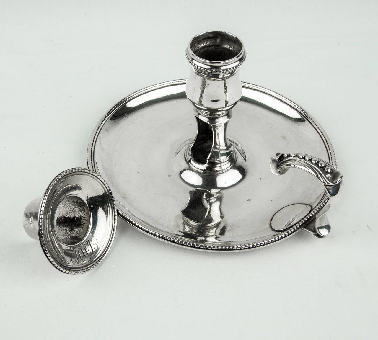 The George III sterling silver chamber stick of circular form with beaded borders and thumb rest; hallmarks correspond to: John Crouch, London, England, circa 1777; approx. Dimensions: 5.25”diameter x 3.5” high; 233.1 gm.
Chamber sticks first made
