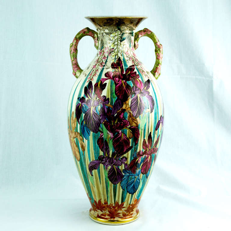 Satsuma ovoid form two handled pottery vase beautifully hand-painted with overall floral designs over ivory ground. The predominant iris motif is surrounded by cascading wisteria blooms in heavy raised enamels above, and red maple leaves below; all