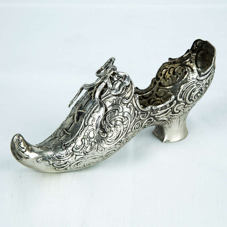 Beautiful ornate silver shoe slipper, exterior has overall hand chased repouse scroll and shell designs, pierced lace front, applied laces and large bow, German 800 silver; marks on the heel, measures approximately 6.5