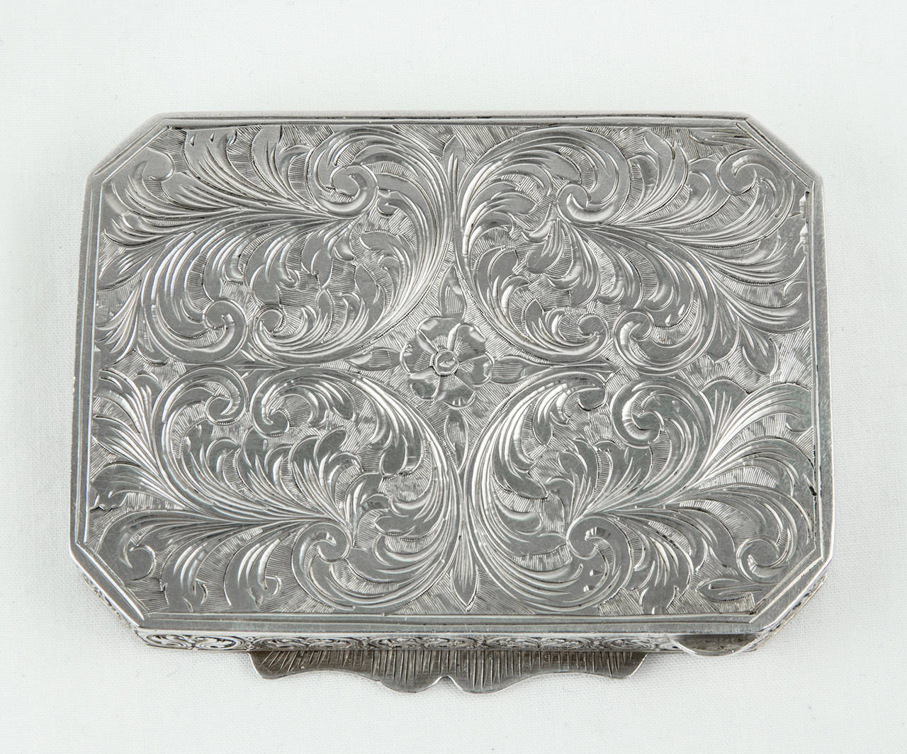 A fine antique rectangular silver and enamel compact box with canted corners, beautifully engraved all-over and with fine hand-painted enameling to the hinged lid. Overall engraving with stylized urns and foliate designs; the engraved lid