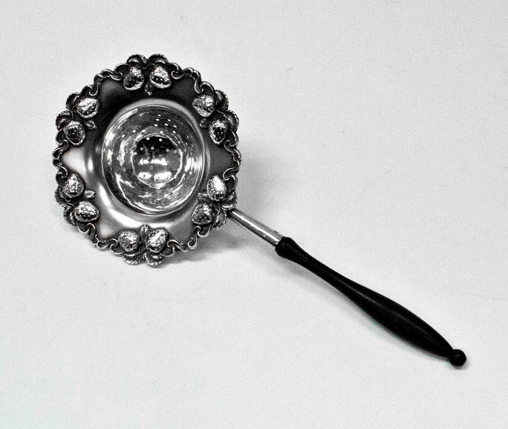 Beautiful sterling silver embossed strawberry and foliate tea strainer with wooden handle. Approximately length 8 1/4 inch strainer bowl, 3 1/2