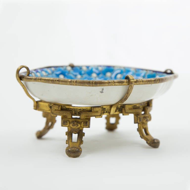 Wavy hexagonal late 19th century French trinket tray in turquoise and white raised enamels on faience, in the Persian style, girded by ormolu stand and cased banding.In the  manner of Eugene Collinot (1824-1889)
Stamped maker's mark to underside.