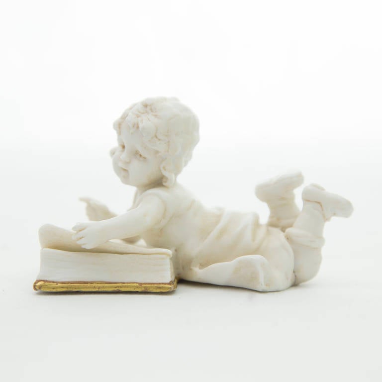 Charming 19th century Bisque figurine depicting an adorable little girl thumbing through a book; 3.5” long x 2.5” high; Mark on bottom corresponds to: SCHWARZ A-SAALBAHN (Thuringia) Muller, E. & A., 1890.